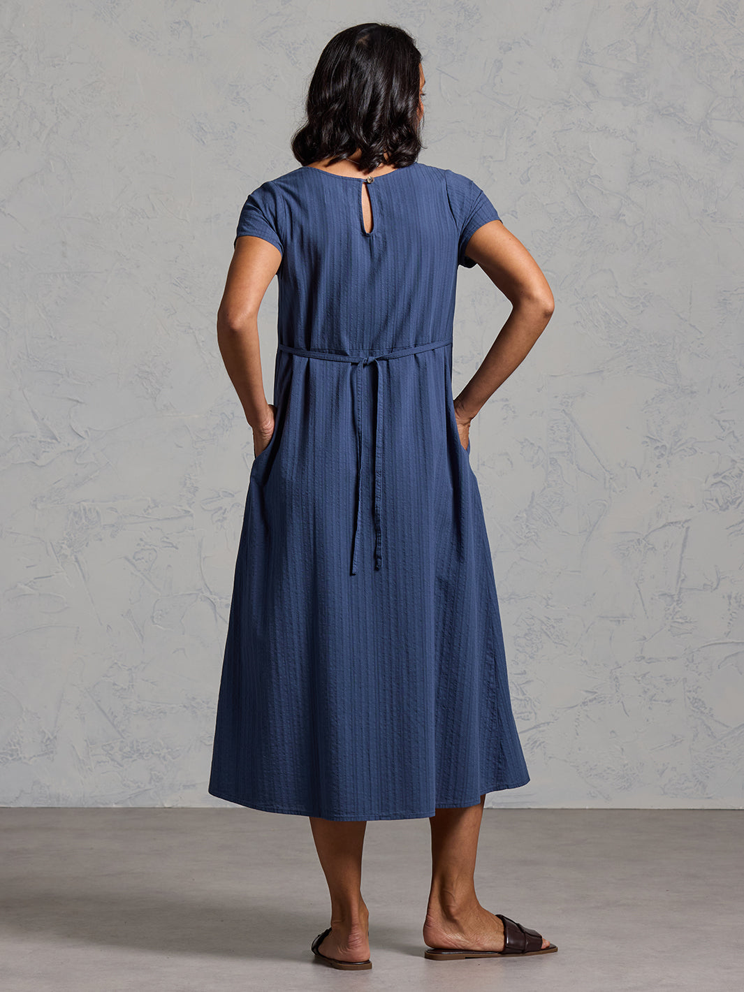A woman wearing a cotton dress in navy from Nomad the Label
