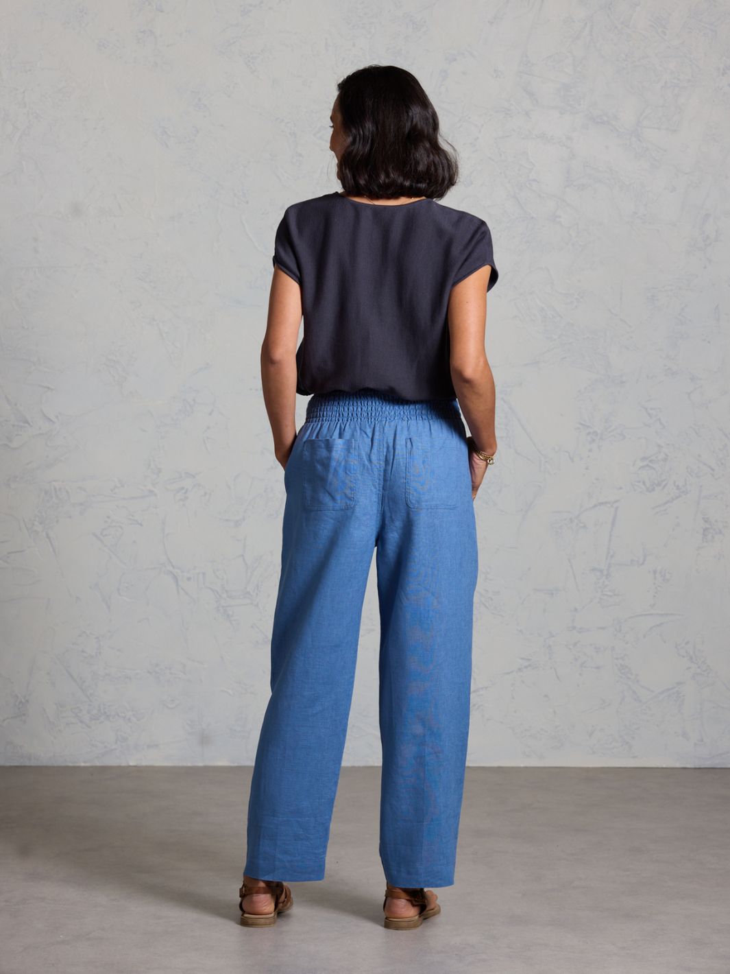 Person wearing a dark top and blue pants against a gray background