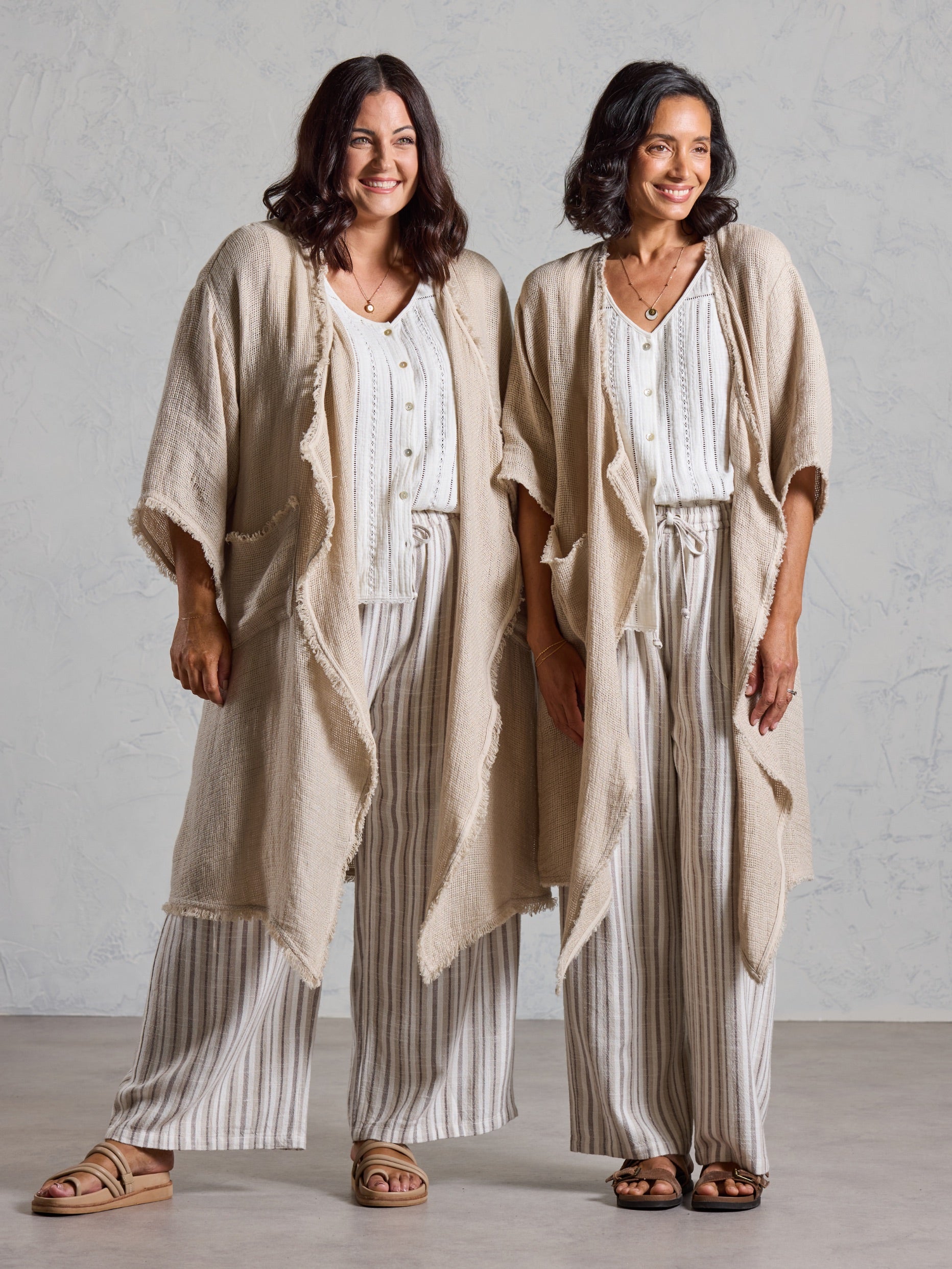 Two models wearing the Laguna French Linen Kimono in natural with white tops and striped linen pants
