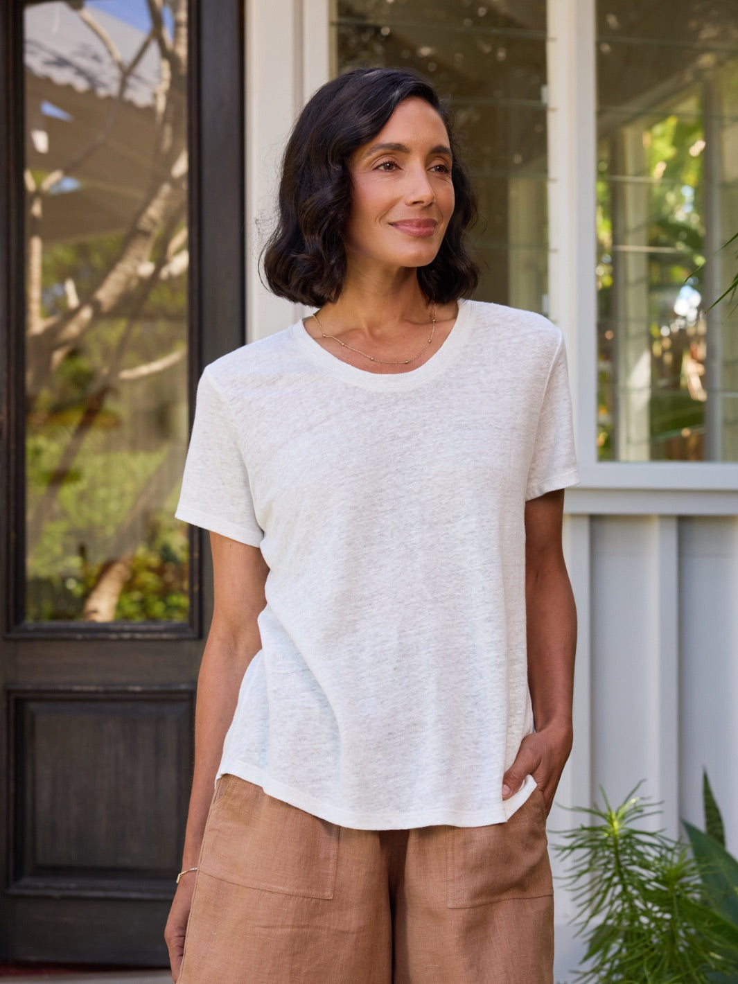 Woman wearing a white t-shirt and brown shorts standing outdoors.