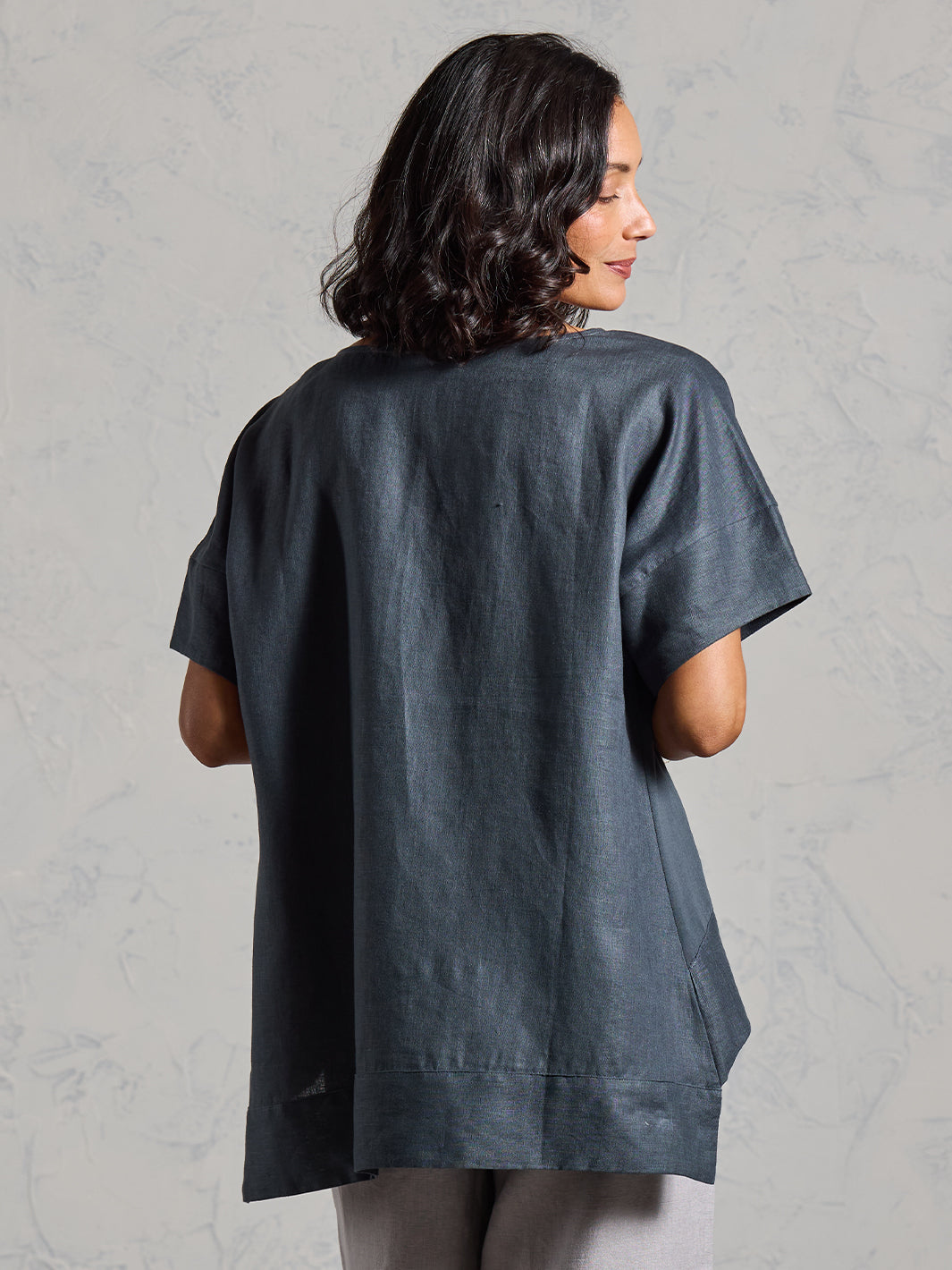 Woman wearing a dark gray t-shirt against a plain background