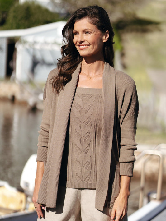 Woman wearing a brown cardigan and sweater by a waterfront