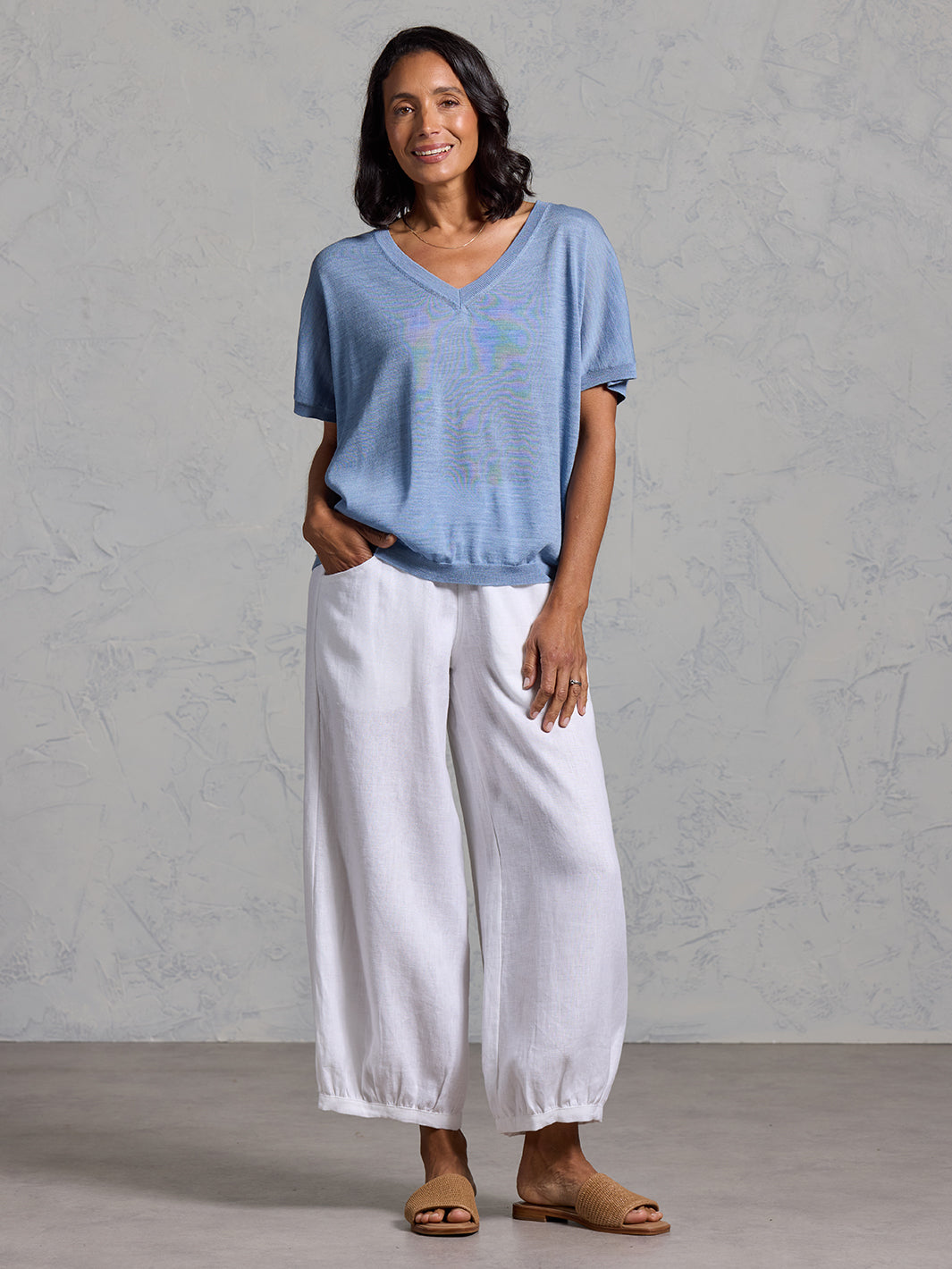 A woman wearing Toscana Merino Wool Top Sea Blue and Sadhu French Linen Pants White