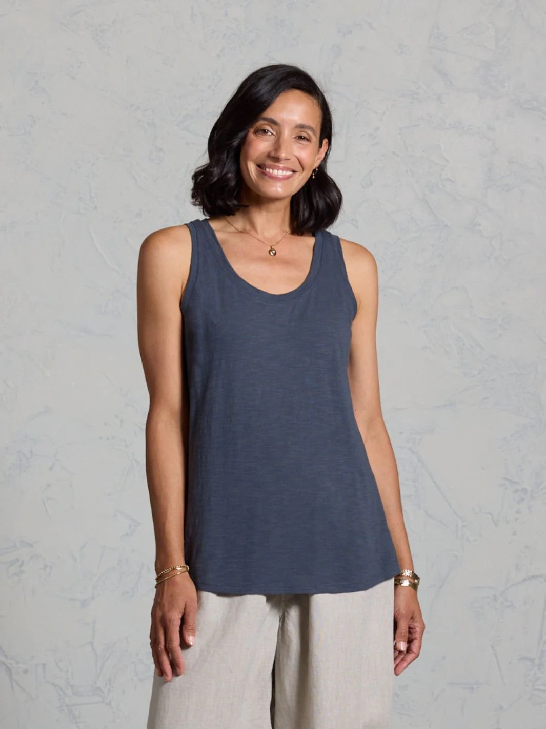 Woman wearing a dark tank top against a gray background