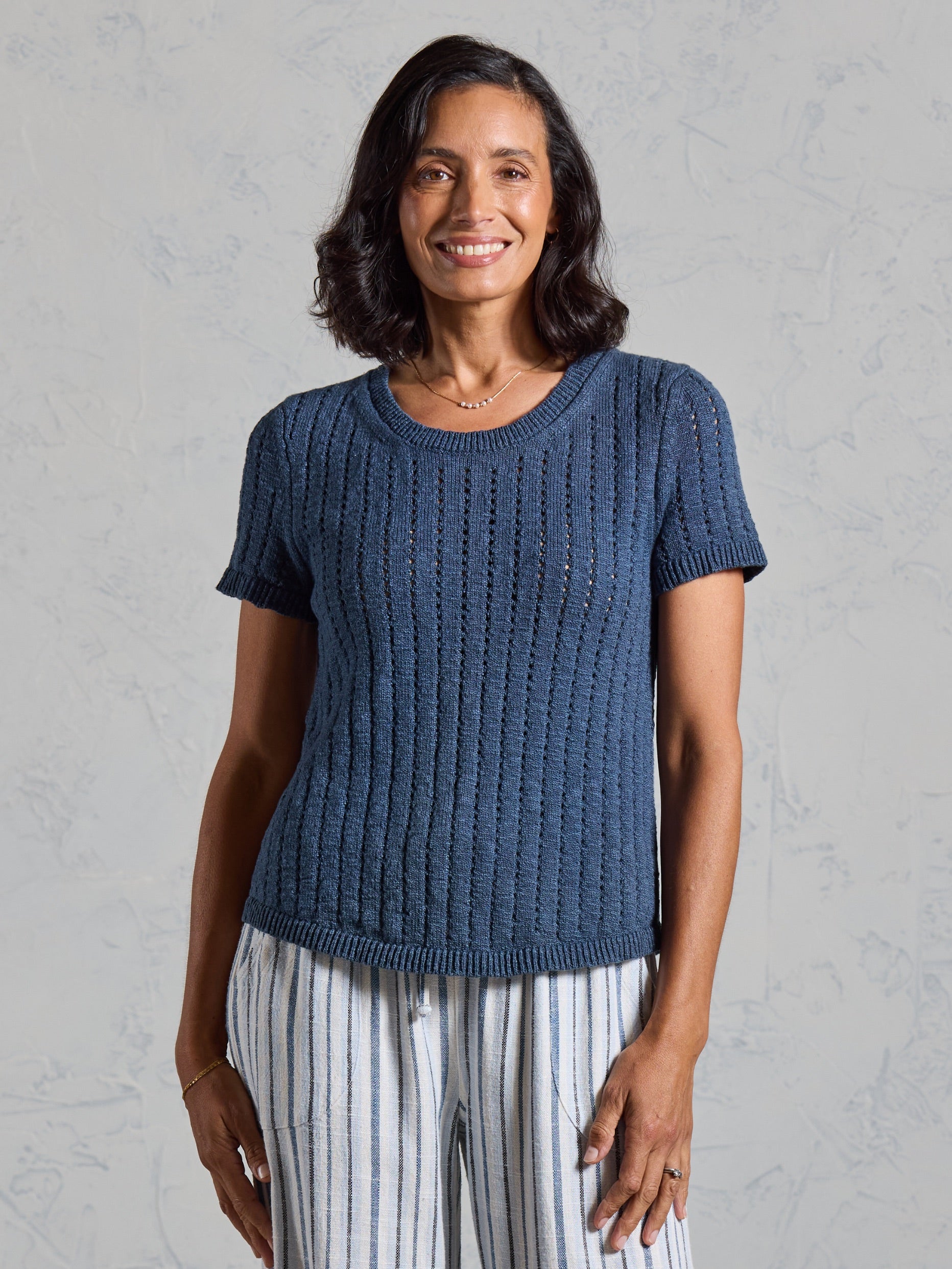 Front view of the Agni Cotton Linen Knit Top in navy, worn with blue and white striped linen pants.