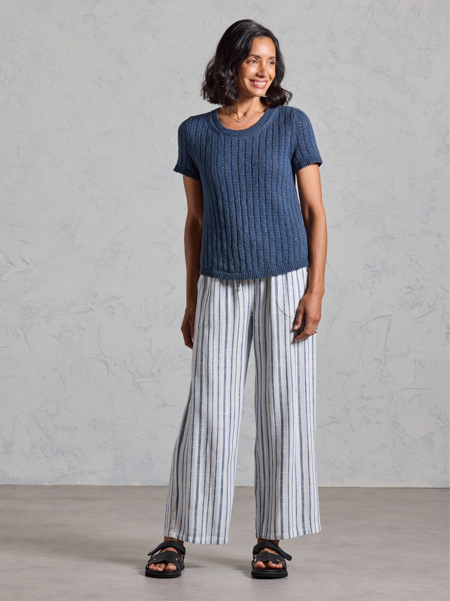 Full length view of the Agni Cotton Linen Knit Top in navy, paired with striped wide leg linen pants.