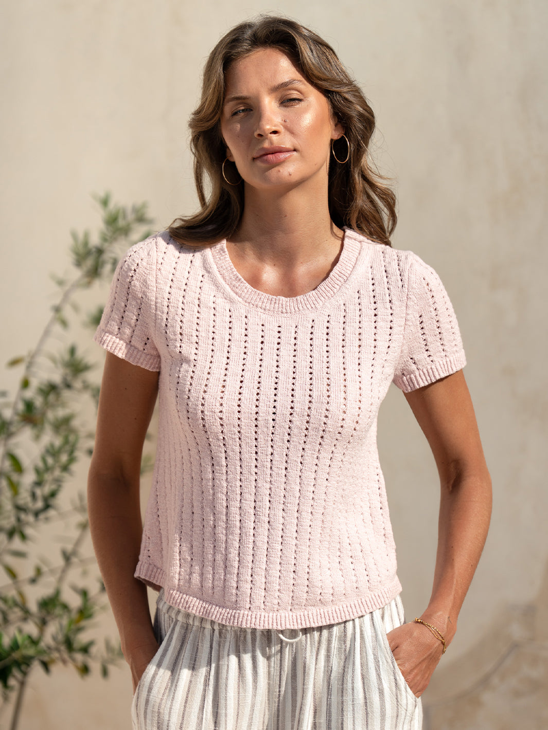 Model wearing the Agni Cotton Linen Knit Top in rosewater, styled with striped linen pants