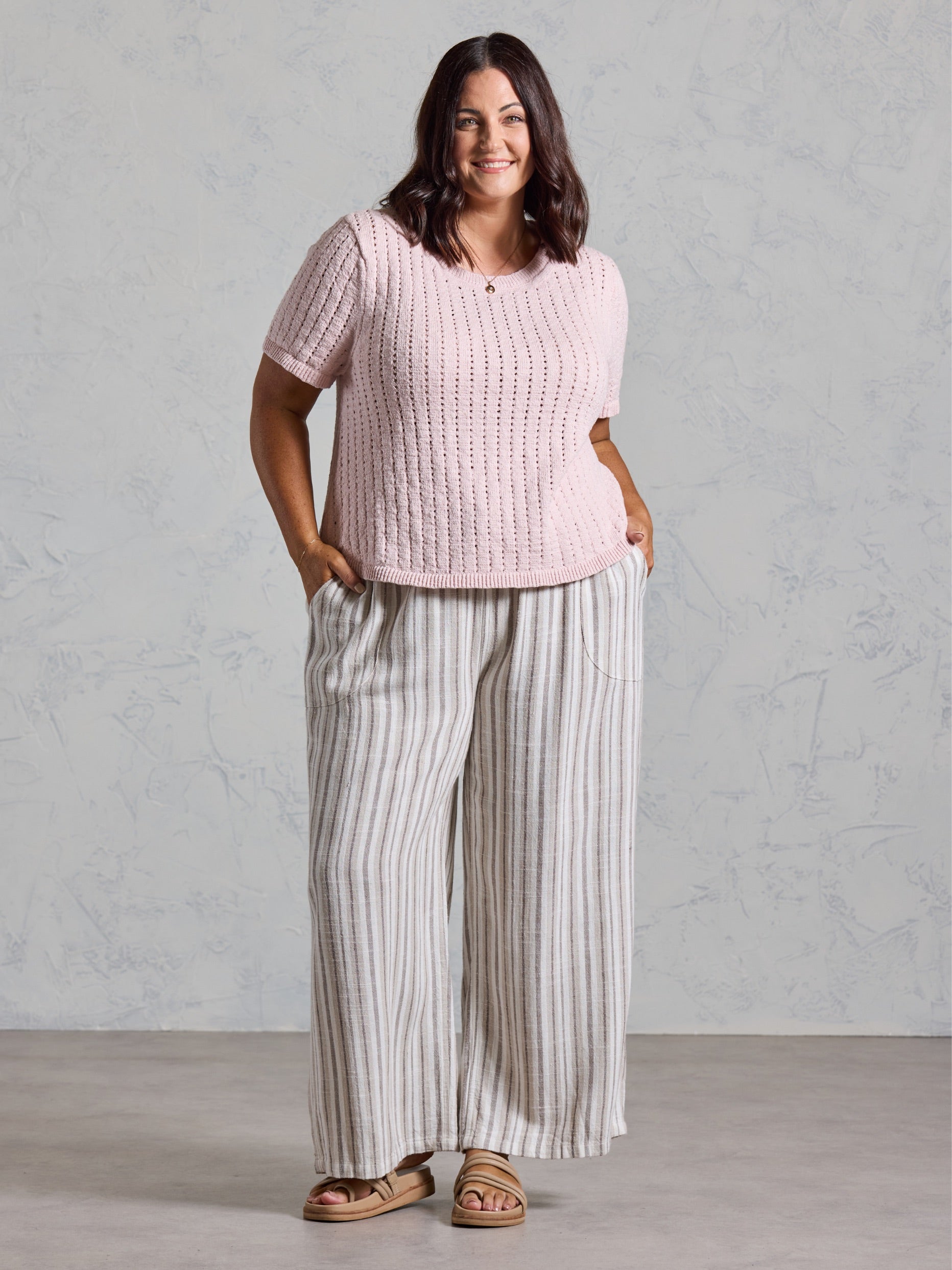 Curve model in the Agni Cotton Linen Knit Top in rosewater, styled with wide leg striped linen pants.