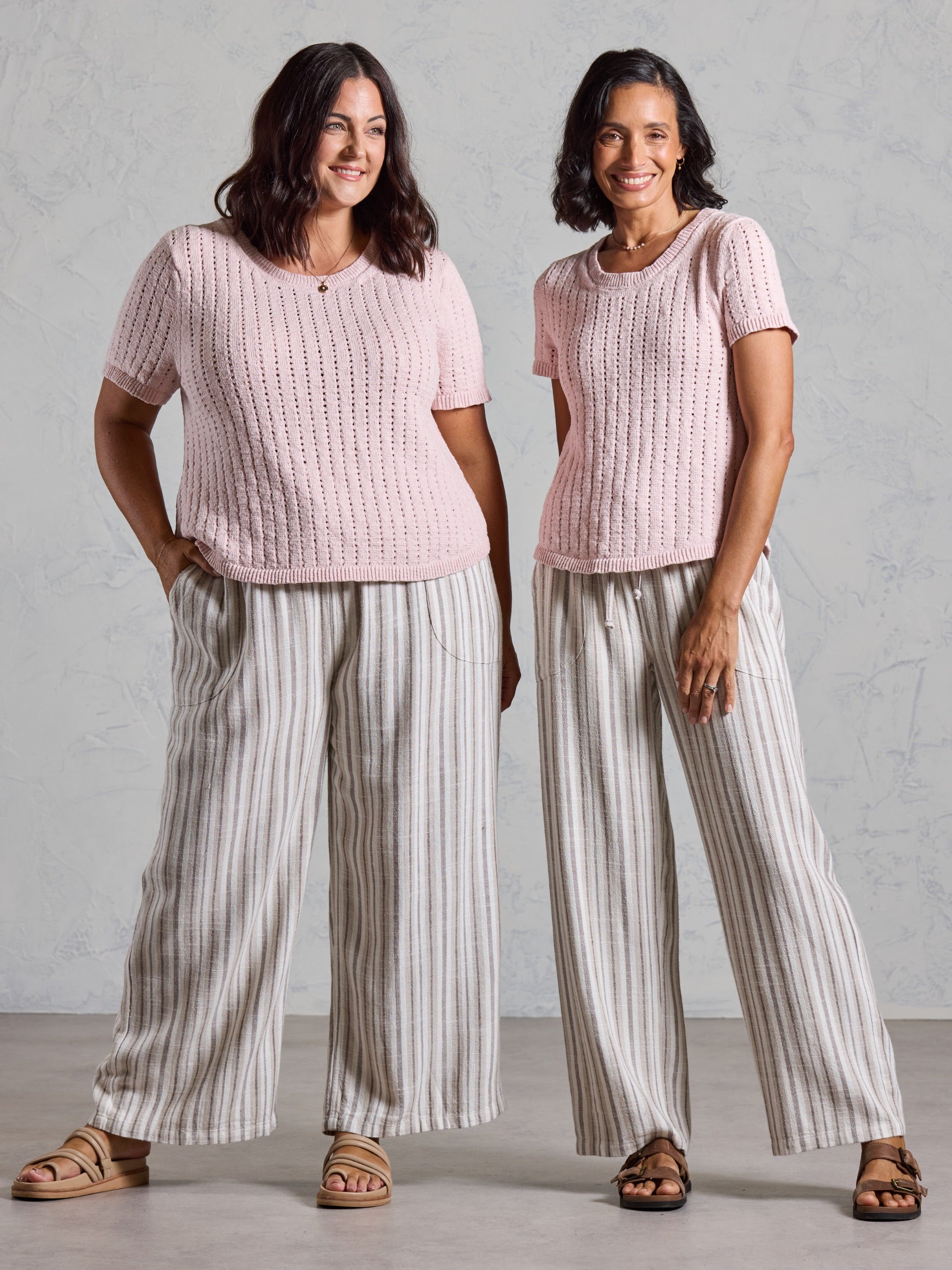 Two models wearing the Agni Cotton Linen Knit Top in rosewater with striped wide leg linen pants