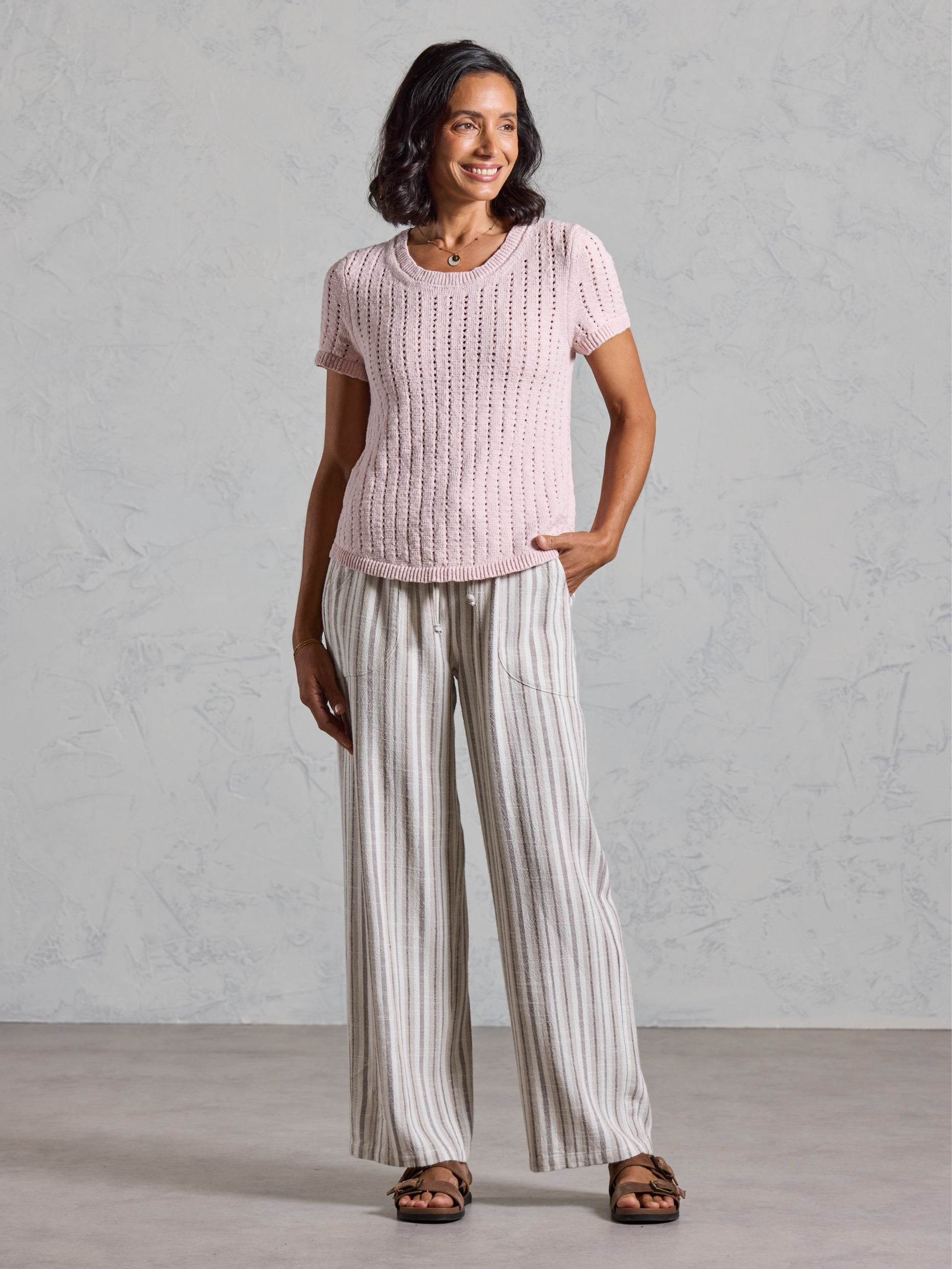 Full length view of the Agni Cotton Linen Knit Top in rosewater, paired with striped wide leg linen pants.