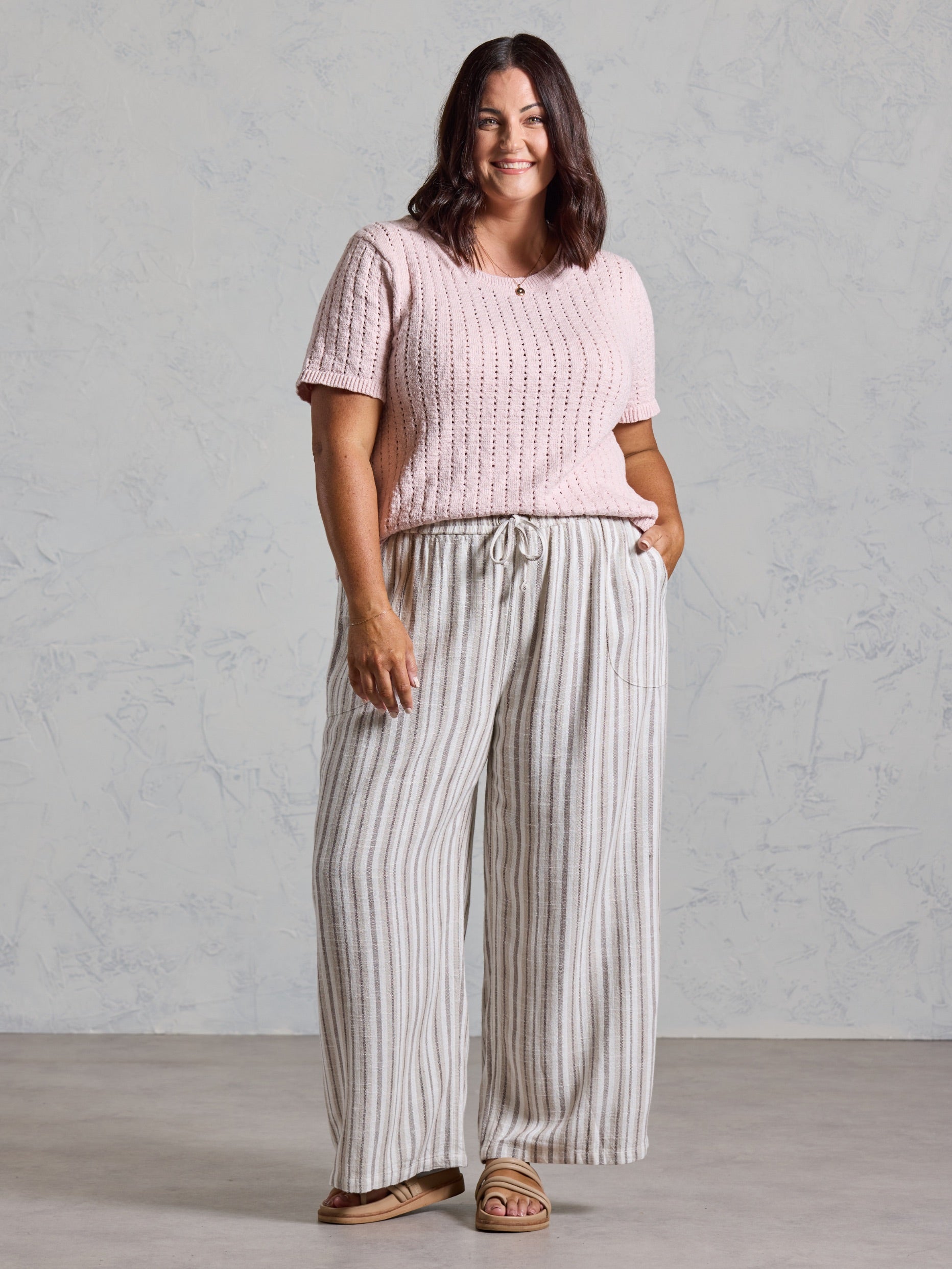 Curve model in the Jolie Linen Blend Trousers in driftwood, styled with a pink knit top.