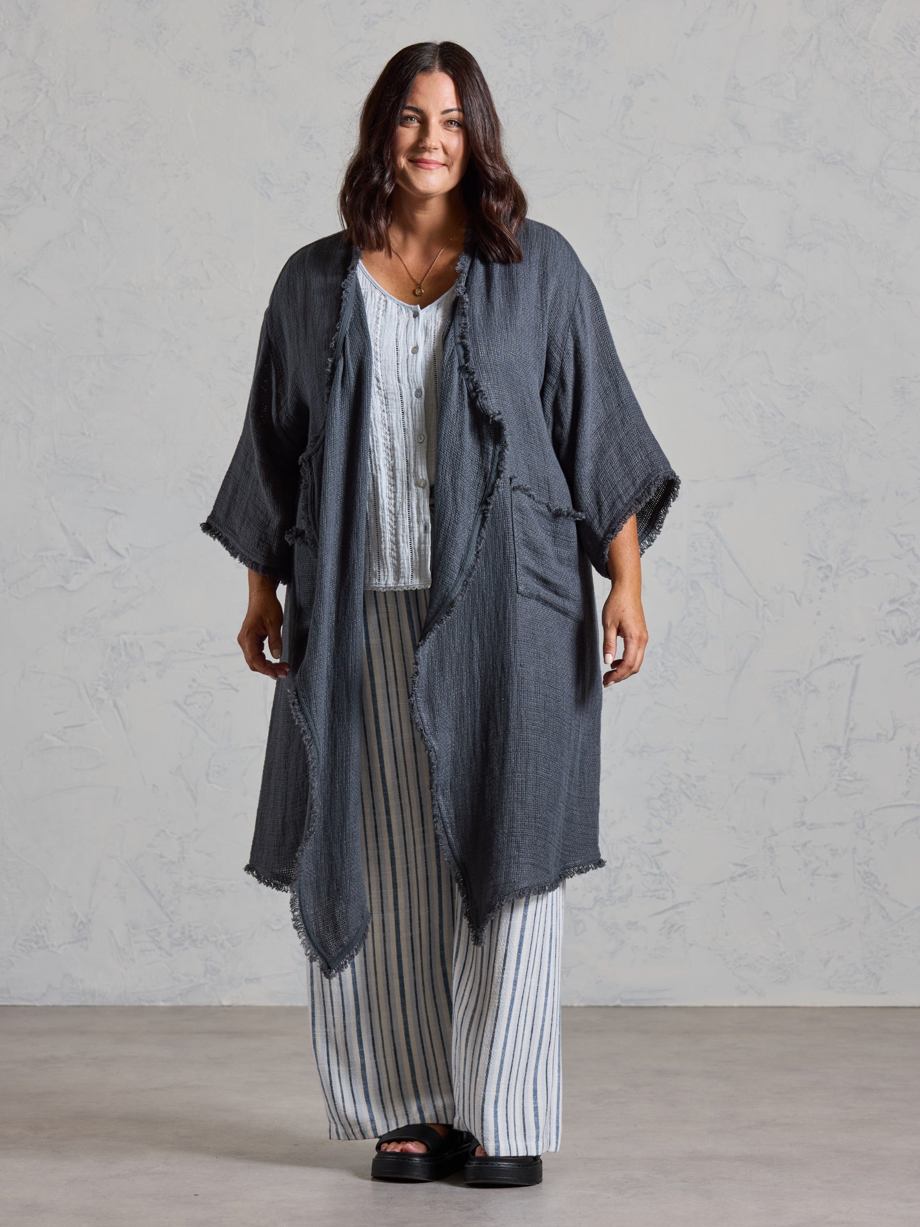 Curve model in the Laguna French Linen Kimono in charcoal, layered over a blue top and striped linen pants.