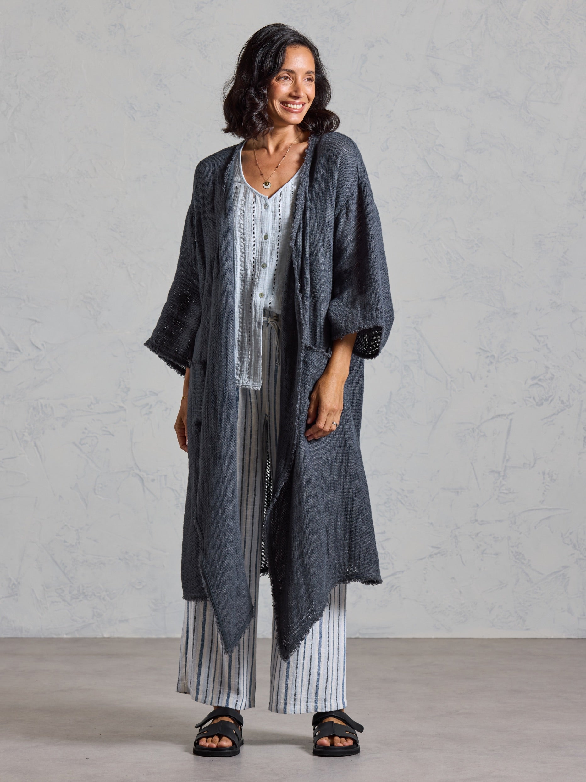 Full length view of the Laguna French Linen Kimono in charcoal, layered over a blue top and striped linen pants.